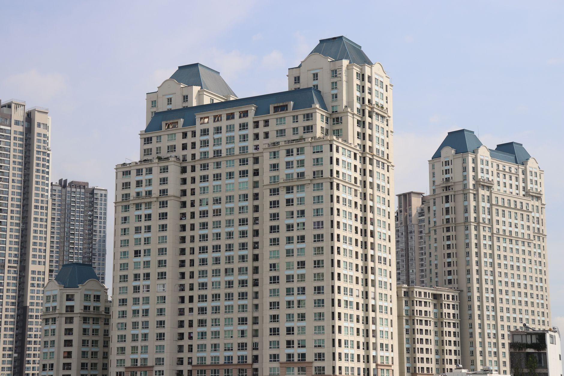 Tampilan modern Aerium Apartemen dengan fasad kaca tinggi, balkon luas, dan taman hijau di tengah kota.